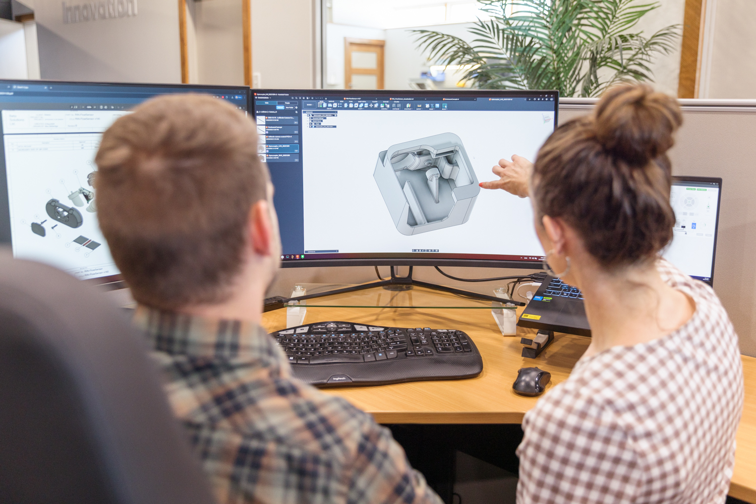 Engineers reviewing 3D CAD model on screen
